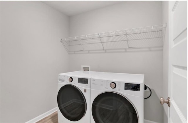 washroom featuring laundry area, wood finished floors, washing machine and dryer, and baseboards