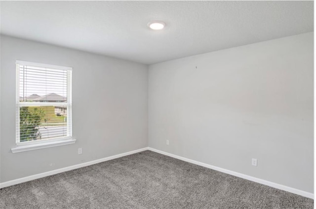 carpeted spare room featuring baseboards