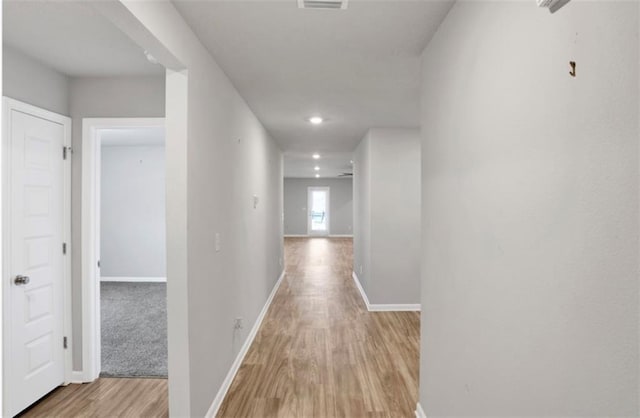 corridor with baseboards and light wood finished floors