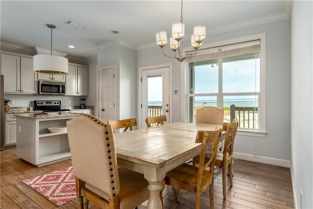 dining space with light wood-style floors, crown molding, and baseboards