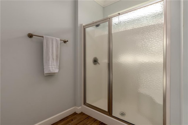 bathroom with a stall shower, wood finished floors, and baseboards