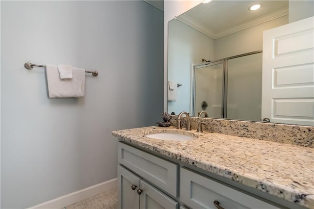 bathroom featuring baseboards, crown molding, vanity, a shower stall, and recessed lighting