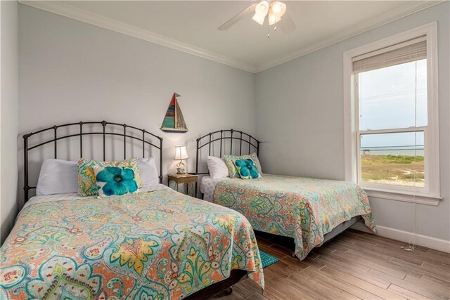 bedroom featuring baseboards, ornamental molding, a ceiling fan, and light wood-style floors