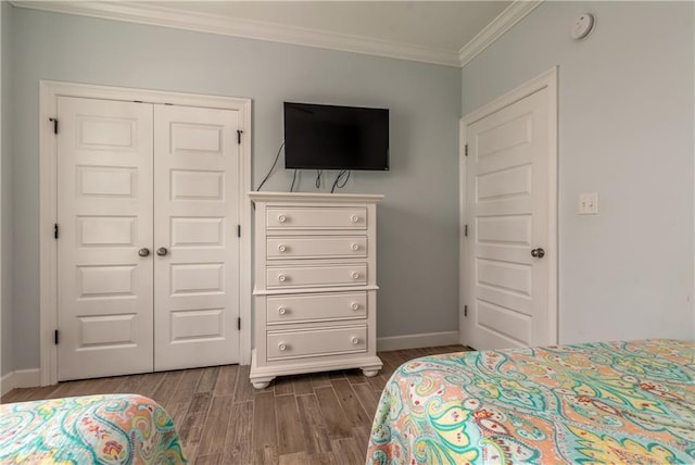 bedroom featuring a closet, crown molding, baseboards, and wood finished floors