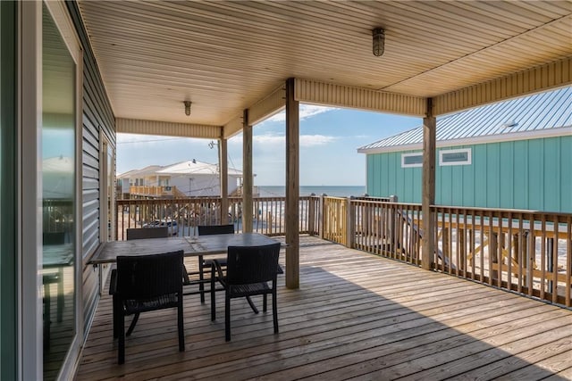 wooden terrace featuring a water view and outdoor dining space