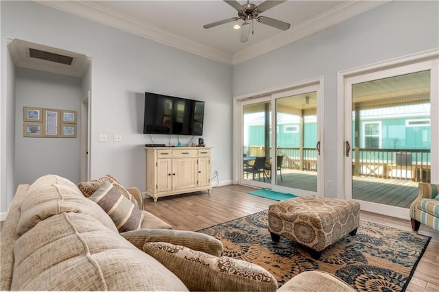 living area featuring ceiling fan, visible vents, baseboards, light wood finished floors, and crown molding