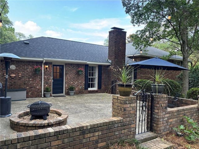 5911 Shenandoah Rd N, Mobile, AL 36608 - back of house with an outdoor fire pit, roof with shingles, a patio area, a chimney, and brick siding