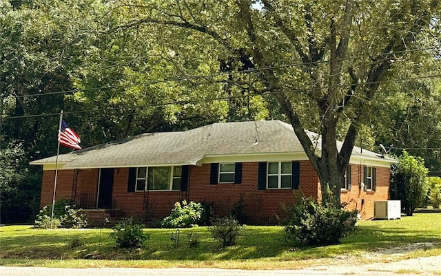 single story home with a front yard, brick siding, and central air condition unit