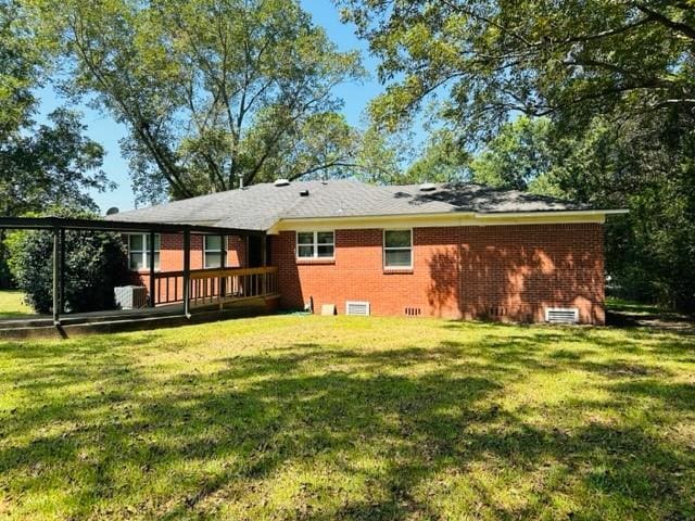 rear view of house with crawl space, brick siding, and a yard