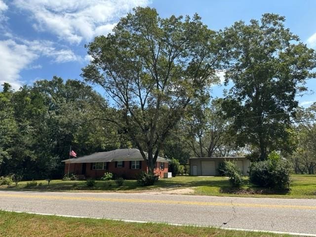 single story home with an attached garage, an outdoor structure, and a front yard