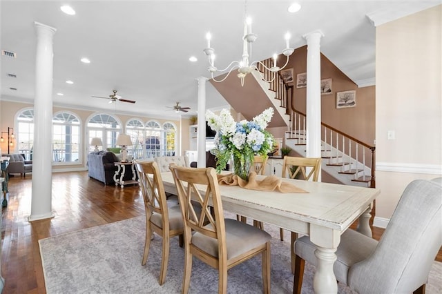 dining room featuring ceiling fan with notable chandelier, crown molding, wood finished floors, and ornate columns