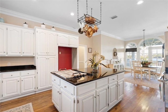 kitchen featuring visible vents, light wood finished floors, ornamental molding, dark countertops, and white cabinetry