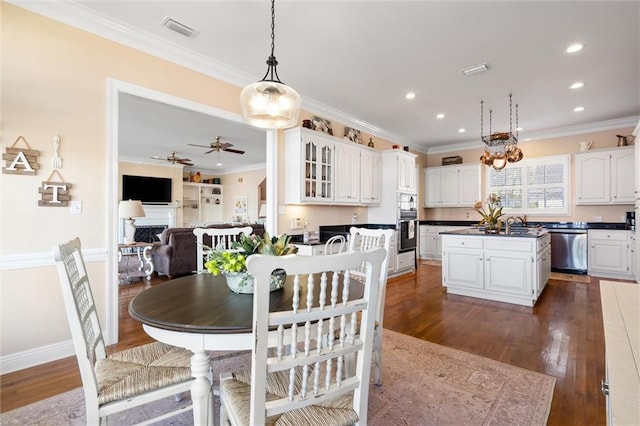 dining room featuring dark wood-style floors, crown molding, ceiling fan, and visible vents