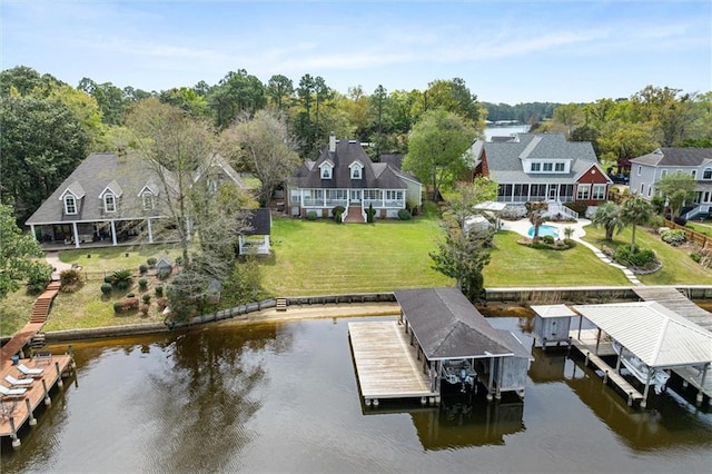 view of dock with a lawn, a water view, boat lift, and a residential view