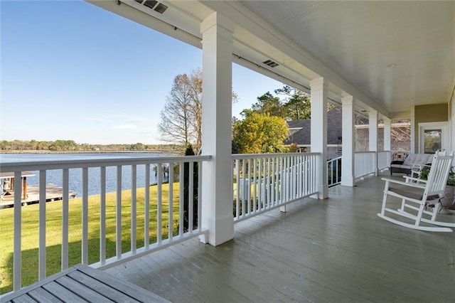 wooden terrace featuring a water view and a yard