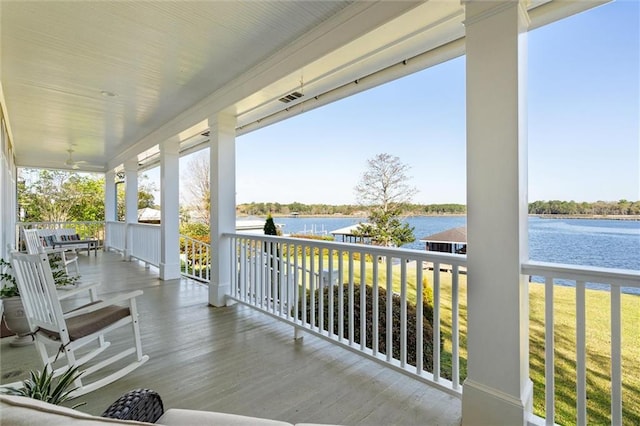 wooden deck with a porch, a water view, and visible vents