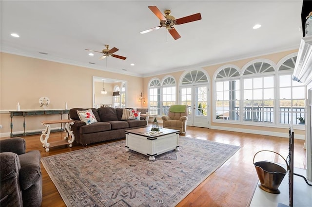 living area featuring a ceiling fan, wood finished floors, baseboards, ornamental molding, and recessed lighting