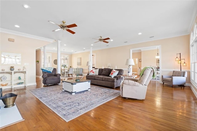 living room featuring wood-type flooring, ornamental molding, and a ceiling fan