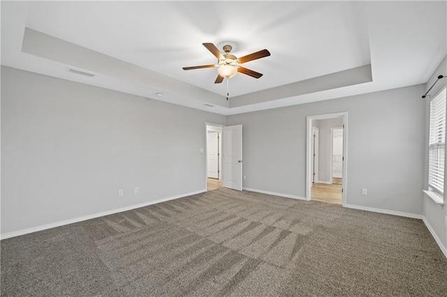 unfurnished bedroom with ceiling fan, carpet floors, connected bathroom, and a tray ceiling