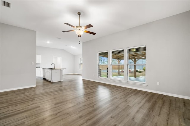 unfurnished living room featuring ceiling fan, sink, dark wood-type flooring, and vaulted ceiling