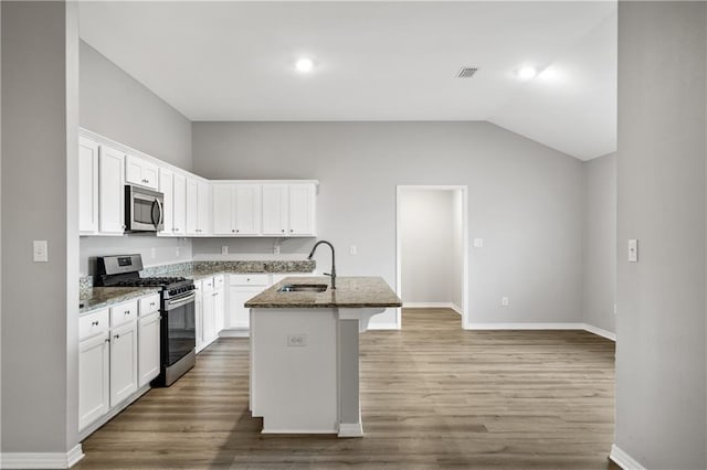 kitchen with sink, a center island with sink, stone countertops, and appliances with stainless steel finishes