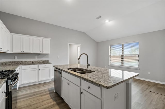 kitchen featuring light stone counters, stainless steel appliances, a kitchen island with sink, sink, and white cabinetry