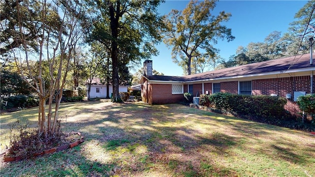 view of front of property featuring a chimney, a front lawn, and brick siding