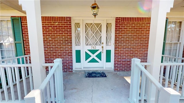 view of exterior entry with covered porch and brick siding