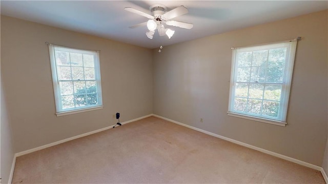 empty room featuring light carpet, ceiling fan, and baseboards