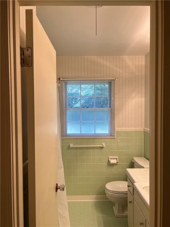 full bathroom with wallpapered walls, a shower with shower curtain, toilet, vanity, and tile walls