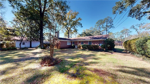 ranch-style house featuring a front yard, brick siding, and a chimney