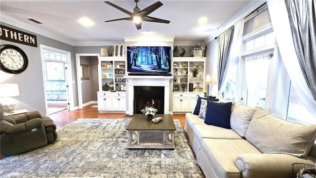 living room with a fireplace, crown molding, a healthy amount of sunlight, and visible vents