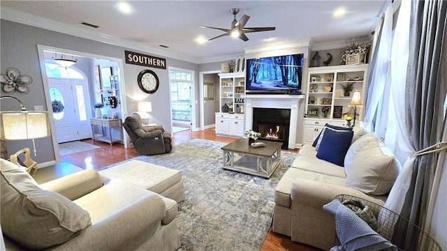 living room with visible vents, plenty of natural light, a warm lit fireplace, and crown molding