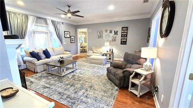 living area with crown molding, wood finished floors, baseboards, and ceiling fan