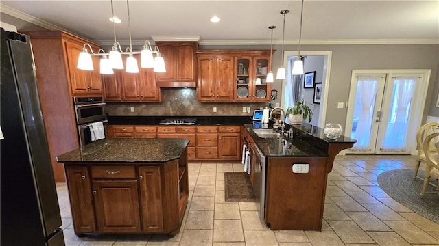 kitchen featuring a peninsula, stainless steel appliances, decorative backsplash, a sink, and glass insert cabinets