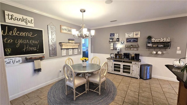 dining room with a notable chandelier, a wainscoted wall, visible vents, and ornamental molding