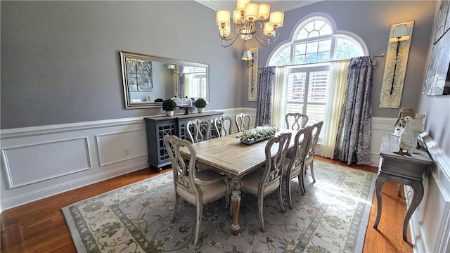 dining space with plenty of natural light, a wainscoted wall, and a chandelier