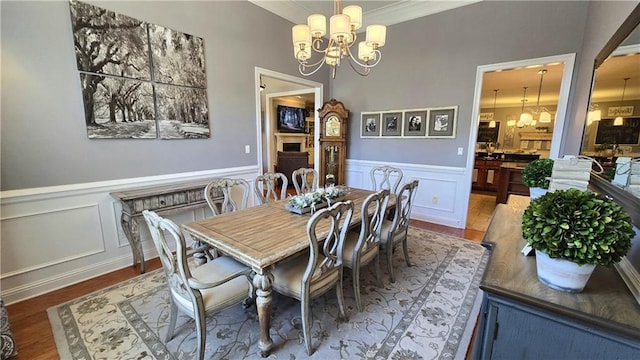 dining space with a wainscoted wall, an inviting chandelier, and wood finished floors