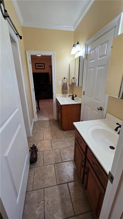 bathroom with a sink, stone tile floors, and crown molding