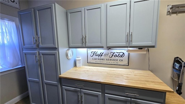 kitchen featuring gray cabinets, wooden counters, and baseboards