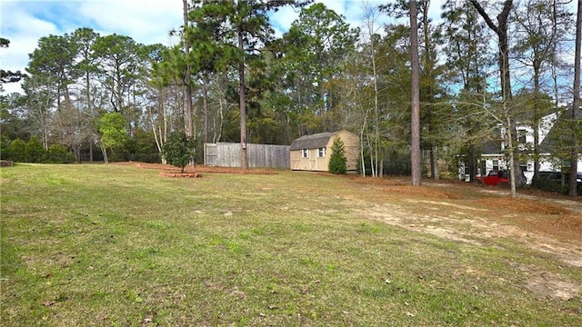 view of yard featuring a storage unit, an outdoor structure, and fence