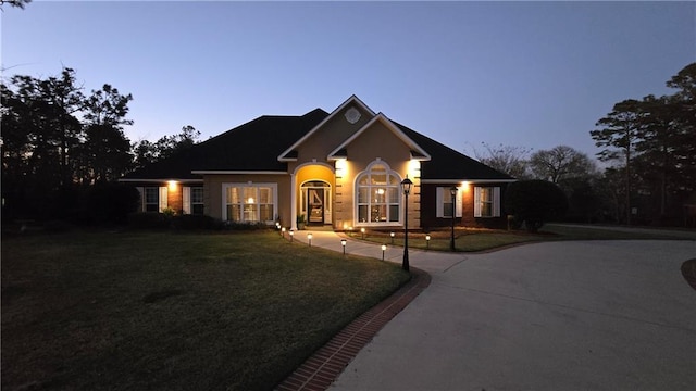 view of front of house with curved driveway and a front yard