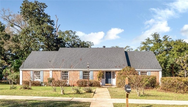 view of front of house featuring brick siding, a front lawn, and roof with shingles