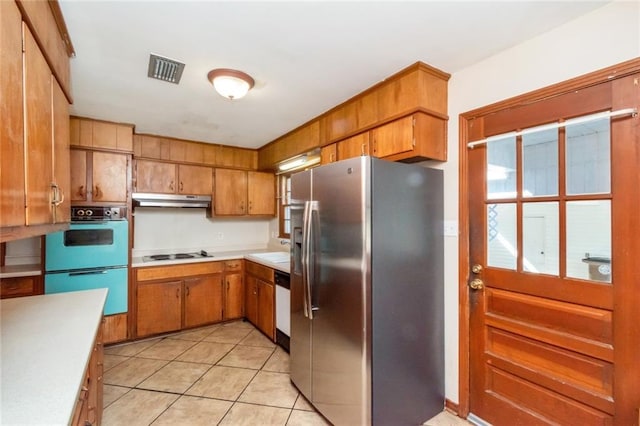 kitchen featuring under cabinet range hood, white stovetop, light countertops, brown cabinets, and stainless steel fridge