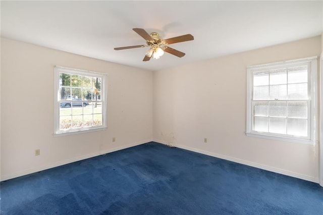 empty room featuring dark carpet, baseboards, and ceiling fan