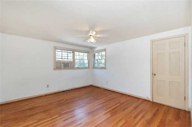 empty room with cooling unit, wood finished floors, a ceiling fan, and baseboards