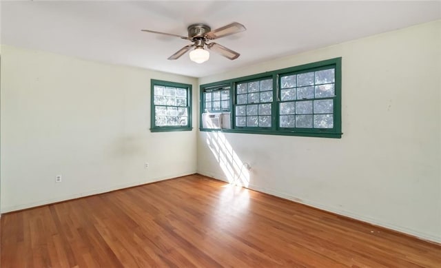 empty room featuring cooling unit, wood finished floors, a ceiling fan, and baseboards