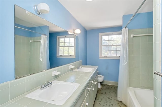 full bath featuring double vanity, shower / tub combo, toilet, and a sink