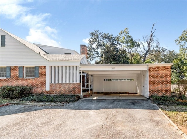 view of front of house with driveway, an attached carport, and brick siding