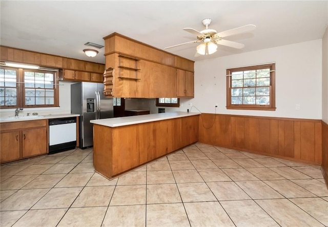 kitchen with stainless steel refrigerator with ice dispenser, light countertops, brown cabinetry, dishwasher, and a peninsula